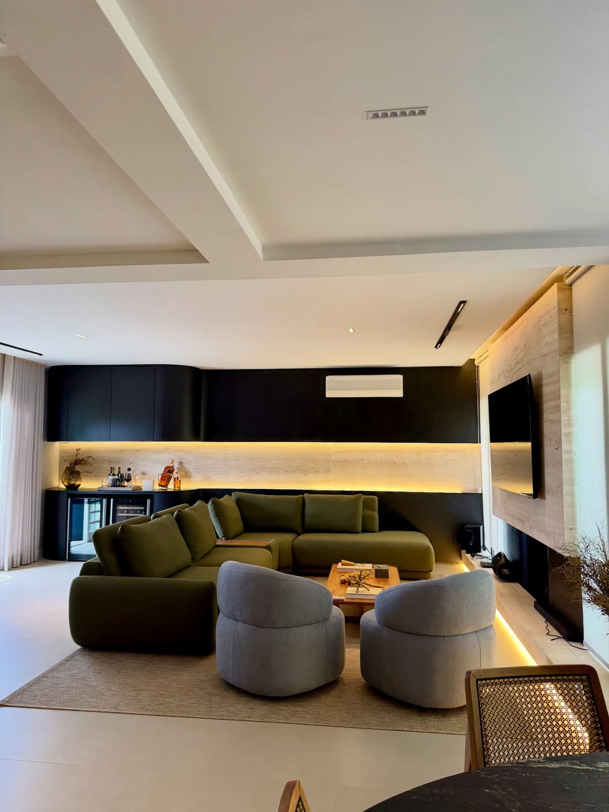 Sala de estar com marcenaria preta, painel de pedra e sofá verde-oliva