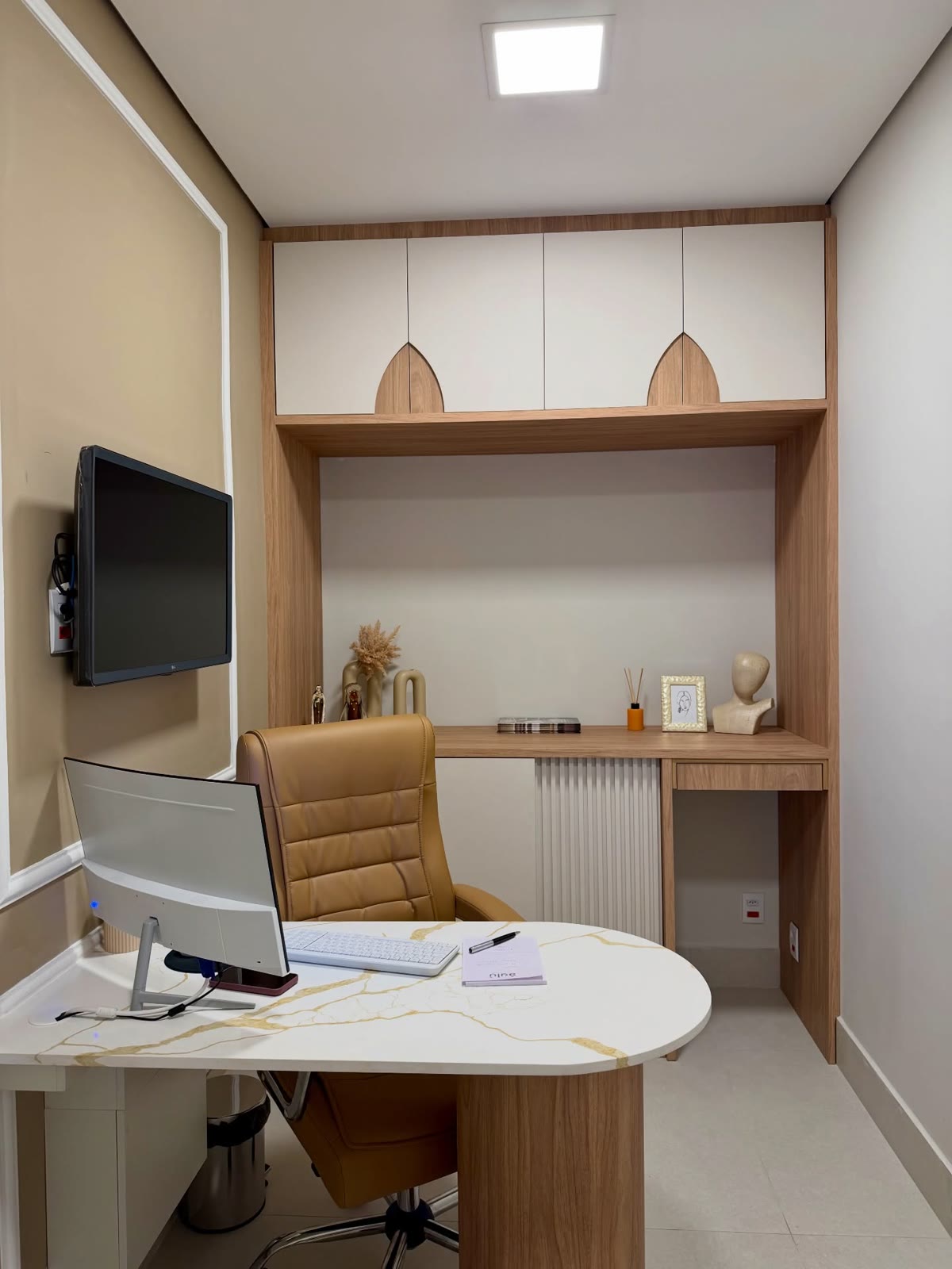 Home office com mesa curva, armários e cadeira de couro caramelo